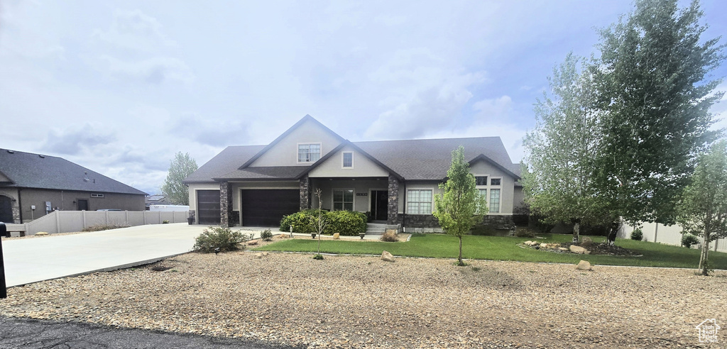 View of front facade with driveway, a garage, and stone siding