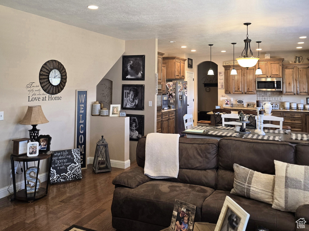 Living area featuring dark wood-type flooring, recessed lighting, baseboards, and a textured ceiling