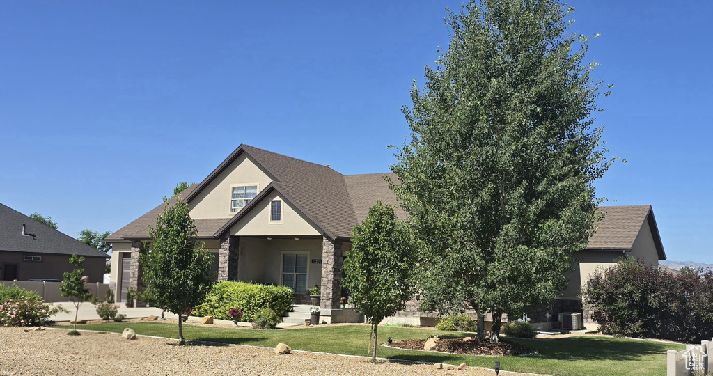 View of front of house featuring stucco siding, a front yard, and stone siding