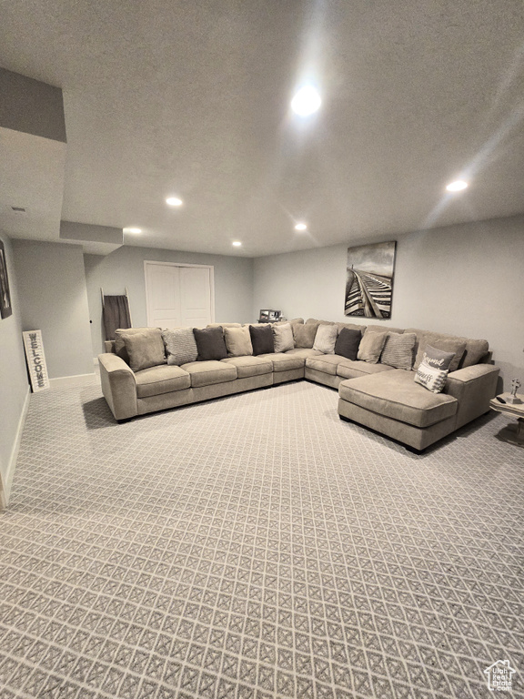 Carpeted living room with recessed lighting, baseboards, and a textured ceiling