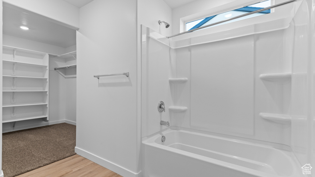 Full bath with baseboards, shower / washtub combination, wood finished floors, and a spacious closet