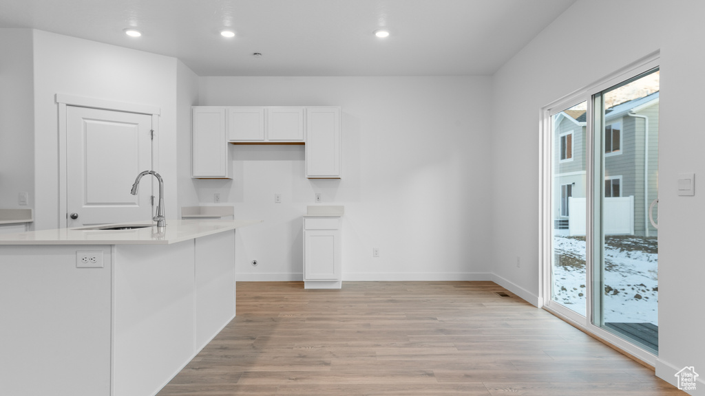 Kitchen featuring a sink, white cabinets, light wood-style floors, recessed lighting, and baseboards