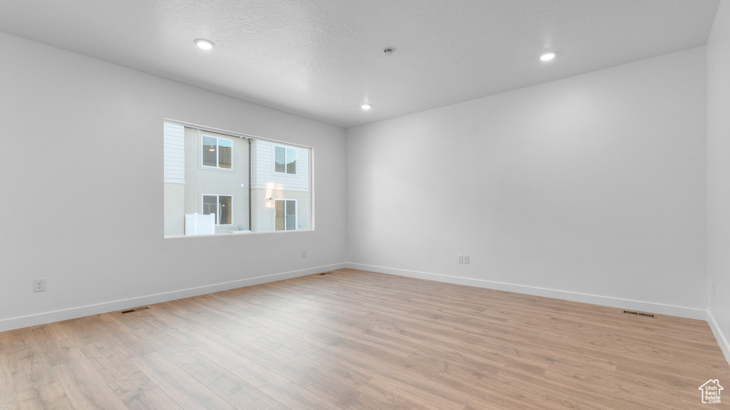 Empty room with light wood-style flooring, baseboards, and recessed lighting