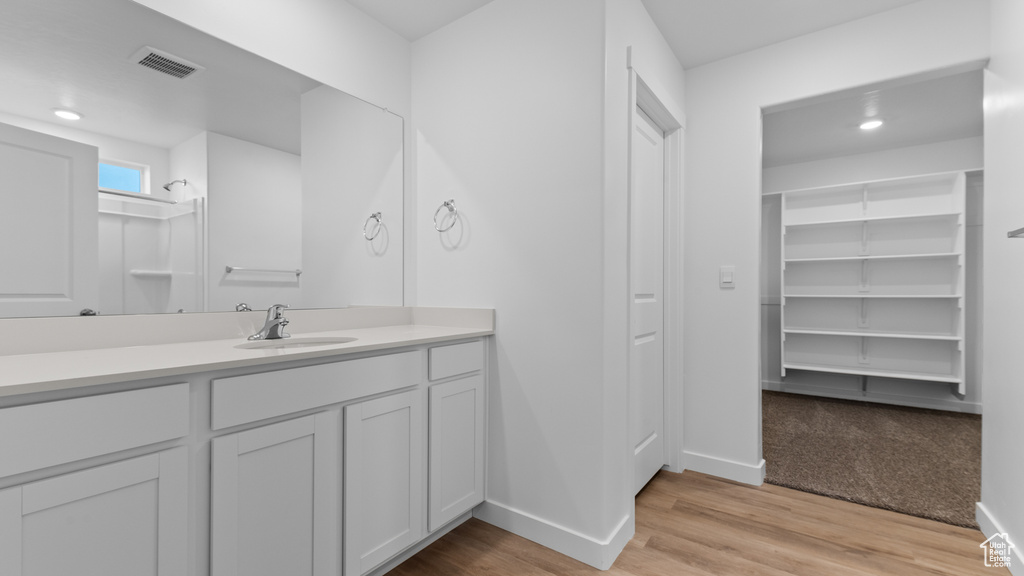 Full bathroom featuring baseboards, vanity, wood finished floors, a spacious closet, and recessed lighting
