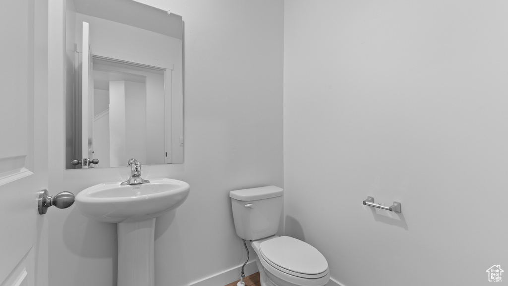 Half bathroom featuring toilet, a sink, and baseboards