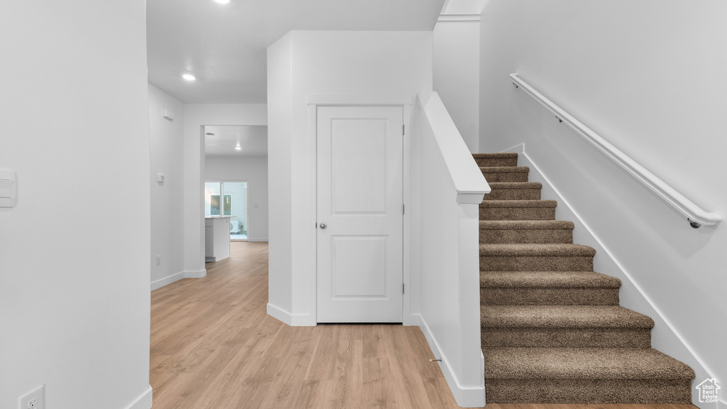 Stairway featuring wood finished floors, recessed lighting, and baseboards