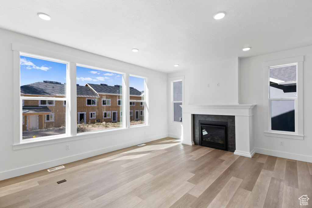 Unfurnished living room featuring baseboards, light wood-type flooring, recessed lighting, and a tile fireplace