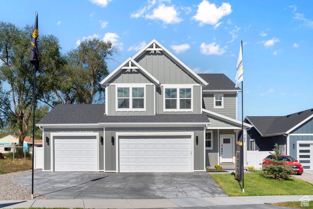 View of front facade featuring board and batten siding, driveway, a garage, and roof with shingles