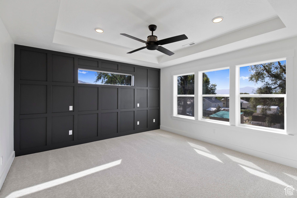 Unfurnished bedroom featuring a tray ceiling, a decorative wall, carpet flooring, recessed lighting, and ceiling fan