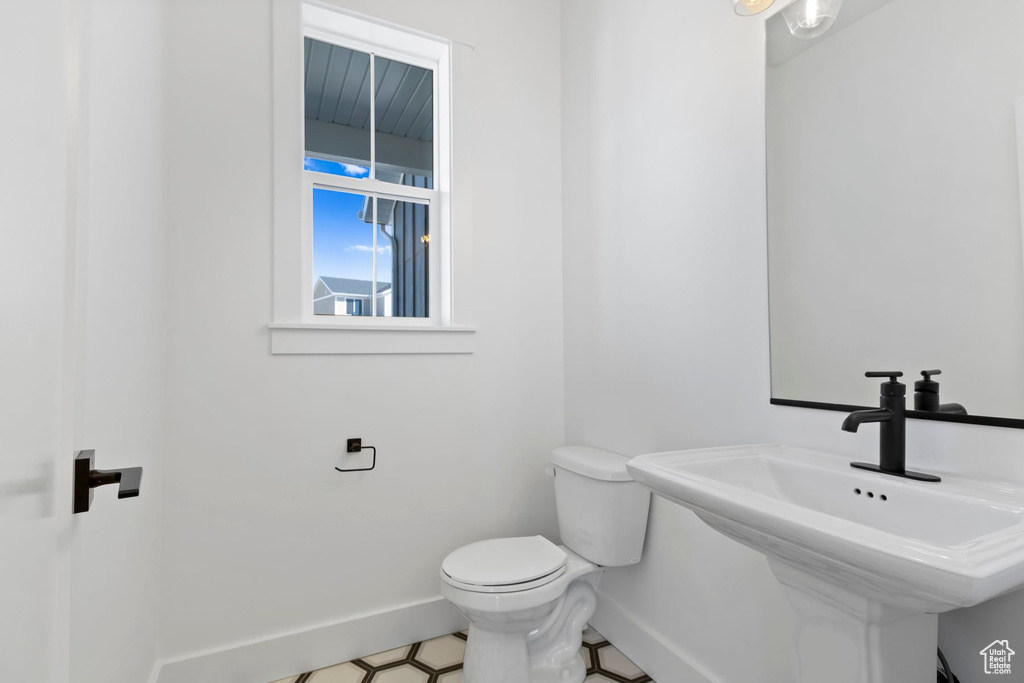 Bathroom featuring baseboards, toilet, and a sink