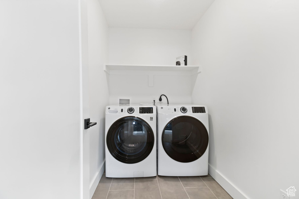 Laundry room with washer and clothes dryer, baseboards, and light tile patterned flooring