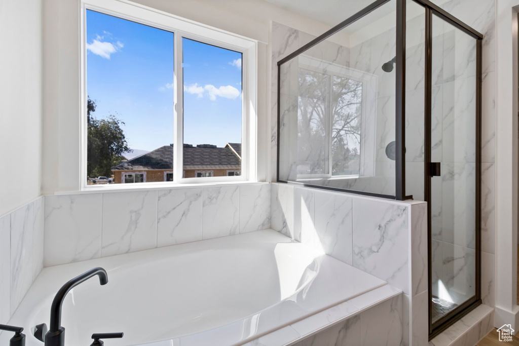 Bathroom featuring a marble finish shower and a garden tub