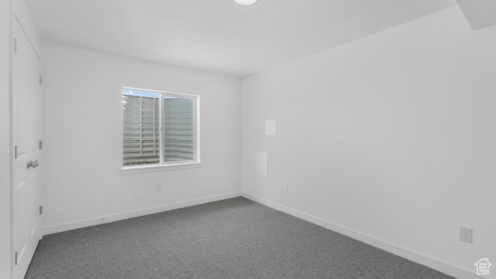 Empty room featuring dark colored carpet and baseboards