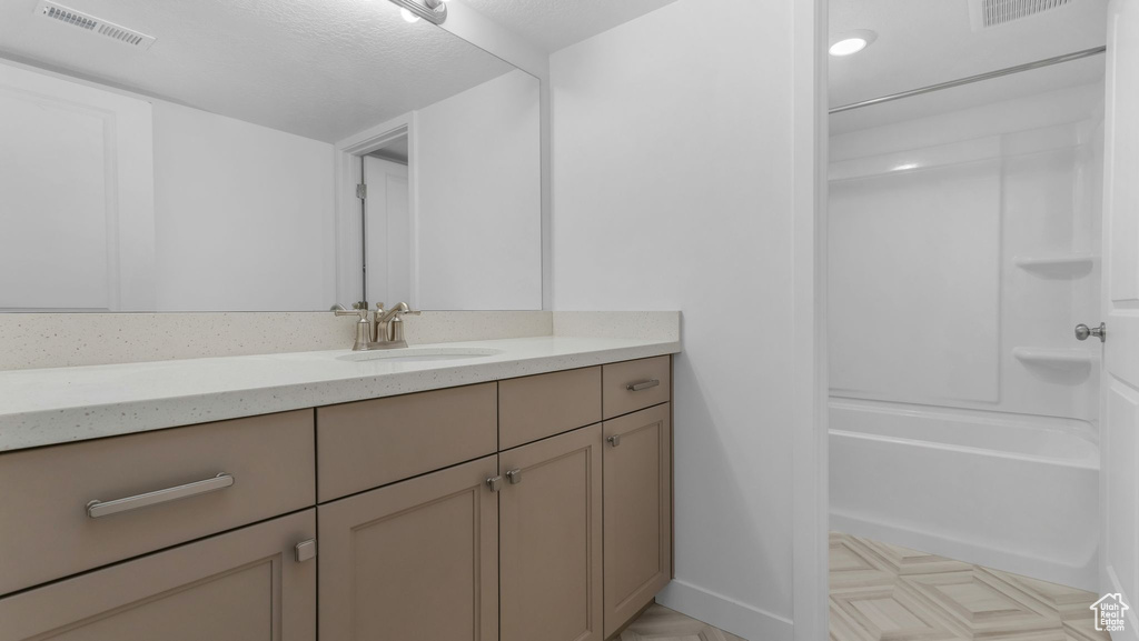 Bathroom with vanity, shower / washtub combination, and baseboards