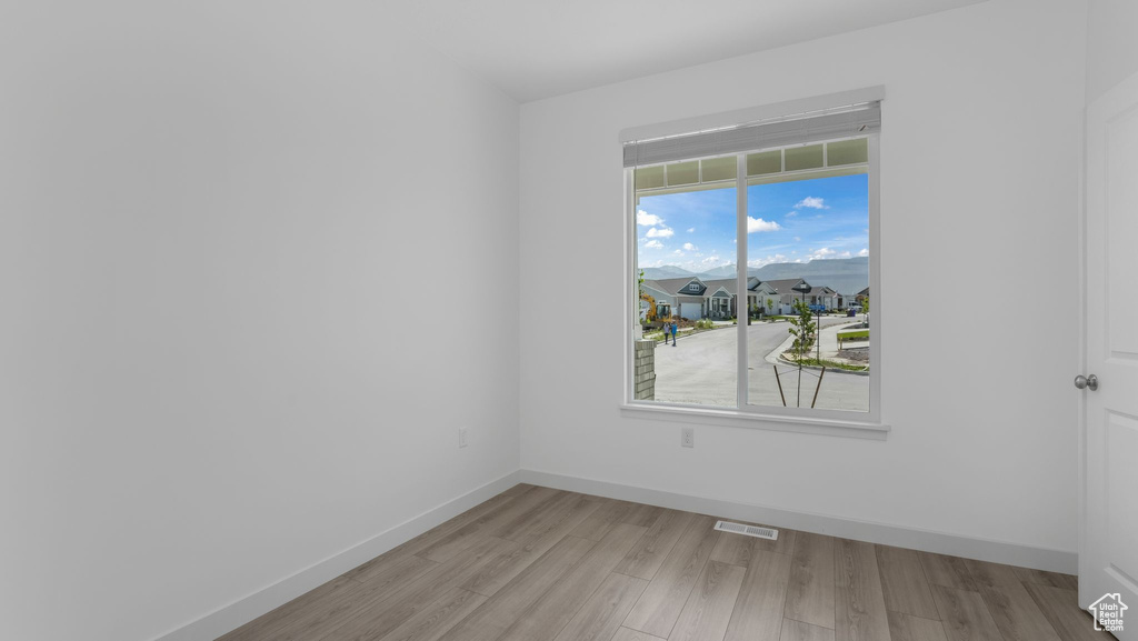 Spare room featuring light wood-style flooring and baseboards