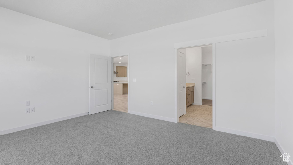 Unfurnished bedroom with light carpet and baseboards