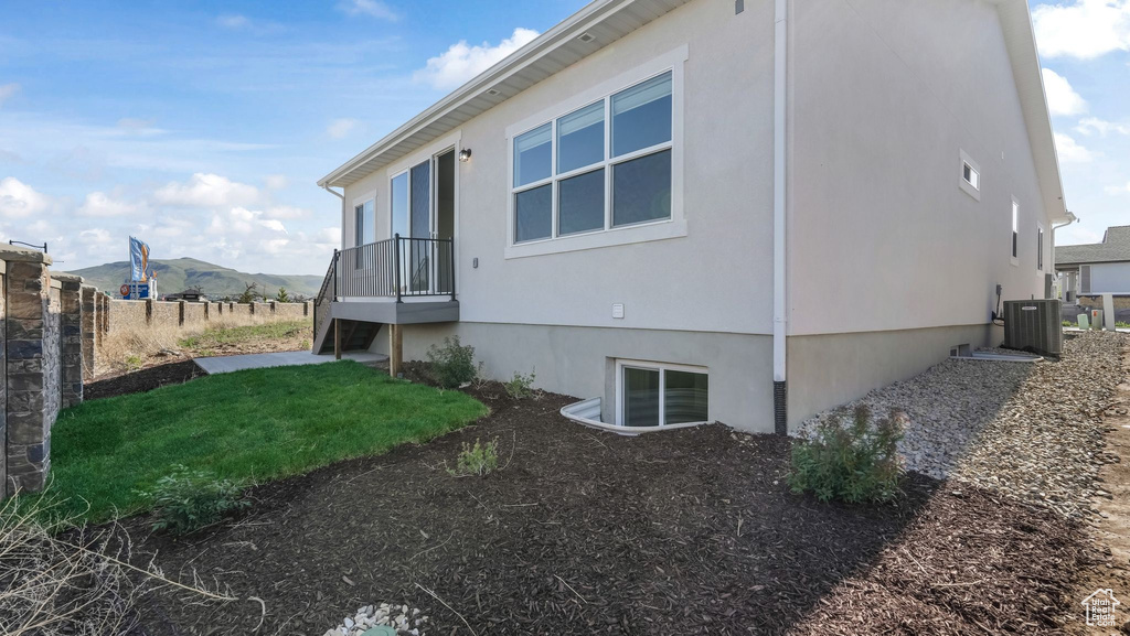 View of side of home featuring central air condition unit, a mountain view, and stucco siding