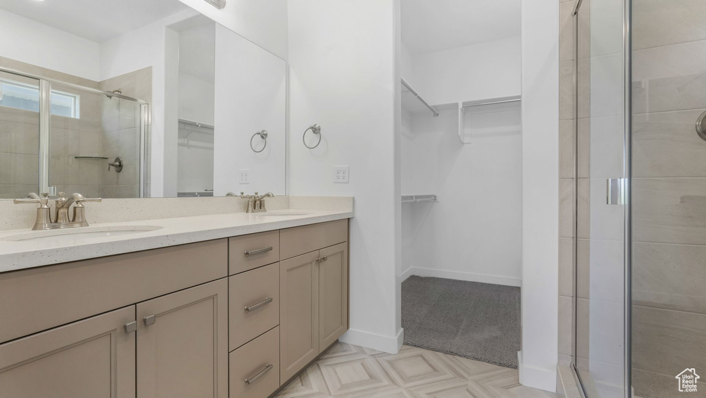 Bathroom featuring double vanity, a stall shower, and a spacious closet