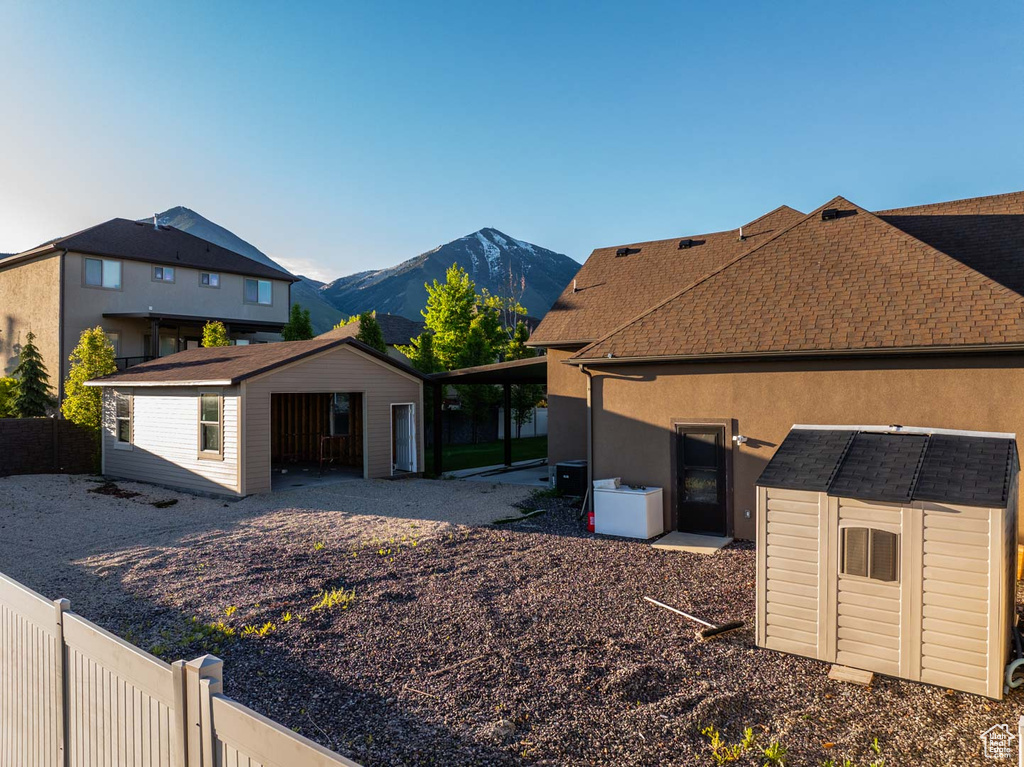View of front of property featuring an outbuilding, a mountain view, a shed, and fence