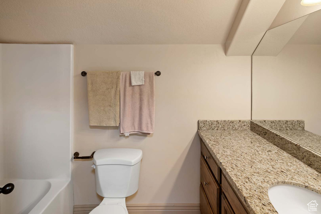 Bathroom featuring vanity, toilet, and baseboards