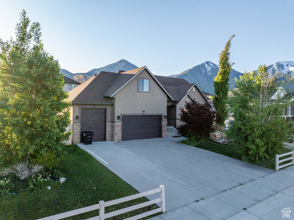 View of front of property with stone siding, driveway, stucco siding, and a mountain view