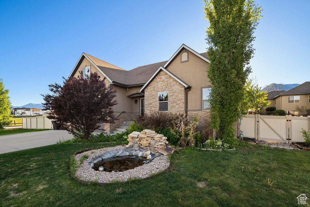 View of front facade with a gate, stone siding, and stucco siding