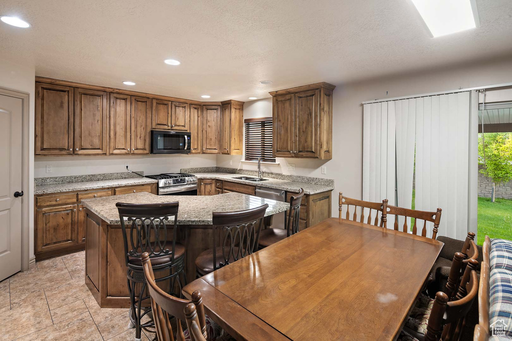Kitchen with stainless steel range with gas cooktop, a sink, a center island, recessed lighting, and a kitchen bar
