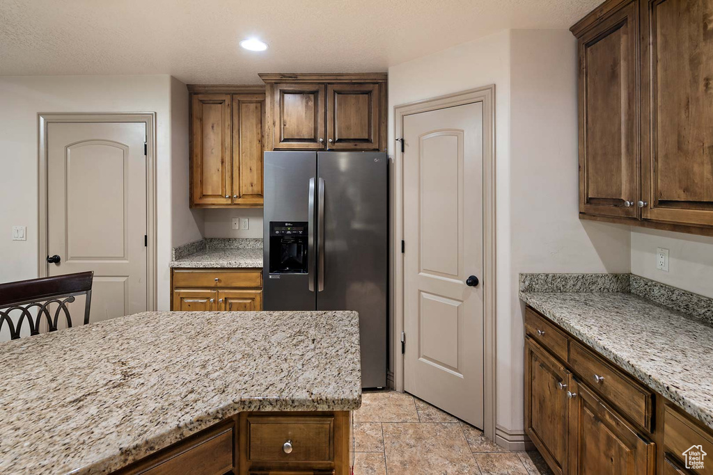 Kitchen featuring stainless steel fridge, light stone countertops, recessed lighting, and light stone finish flooring
