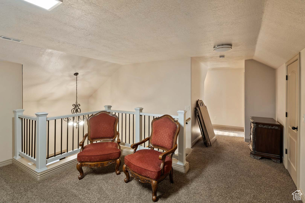 Sitting room with lofted ceiling, a textured ceiling, carpet flooring, an upstairs landing, and baseboards
