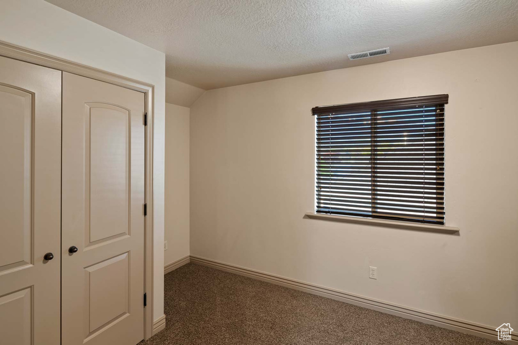 Unfurnished bedroom featuring carpet floors, a closet, a textured ceiling, and baseboards