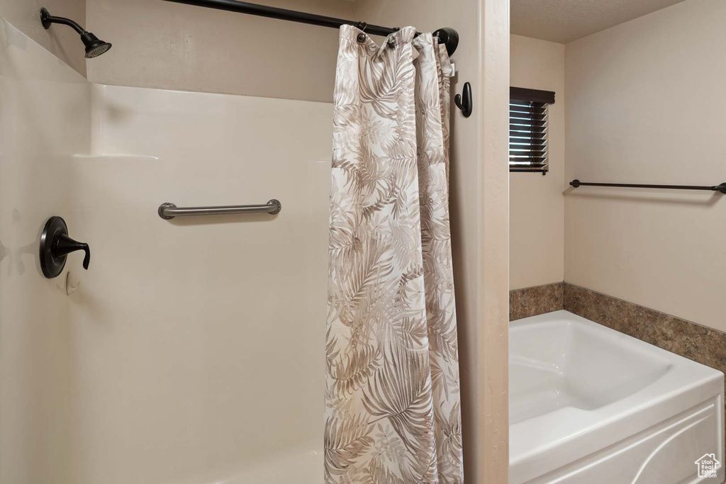 Bathroom featuring curtained shower and a bath