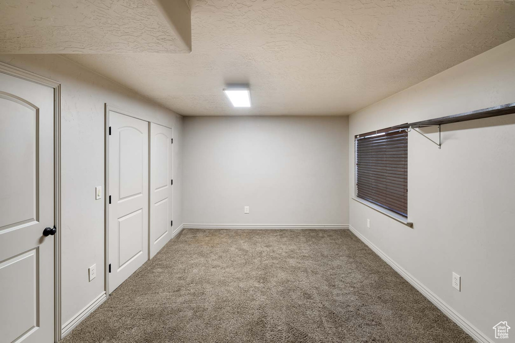 Basement featuring carpet flooring, a textured ceiling, and baseboards