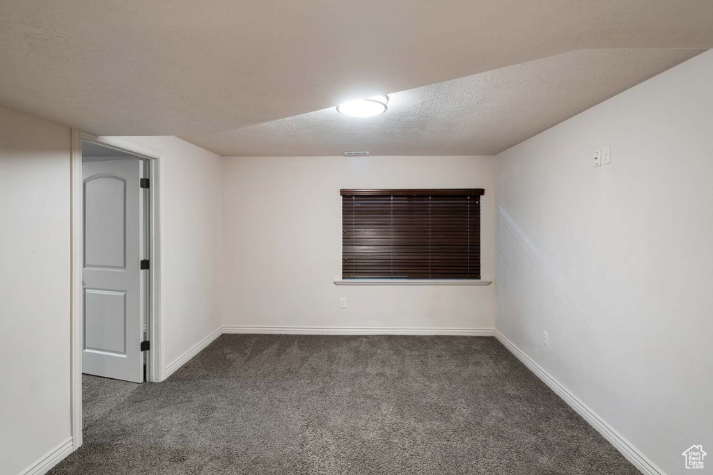 Empty room featuring carpet flooring, baseboards, and a textured ceiling