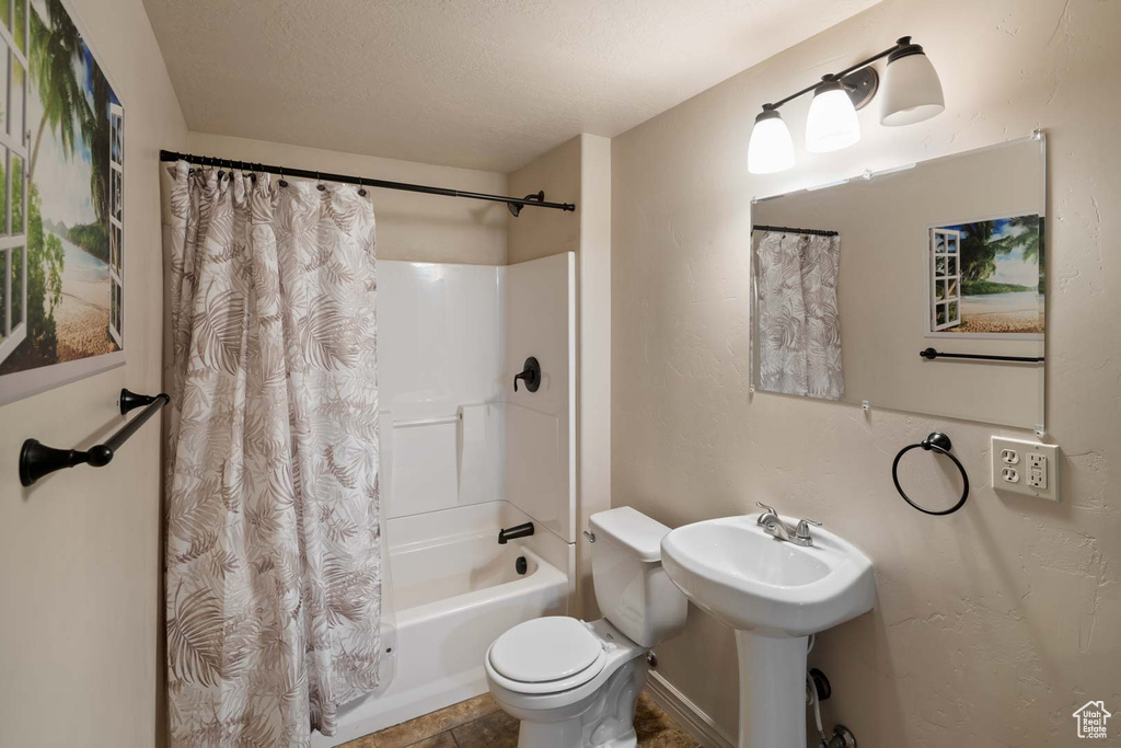 Full bathroom featuring toilet and shower / bathtub combination with curtain