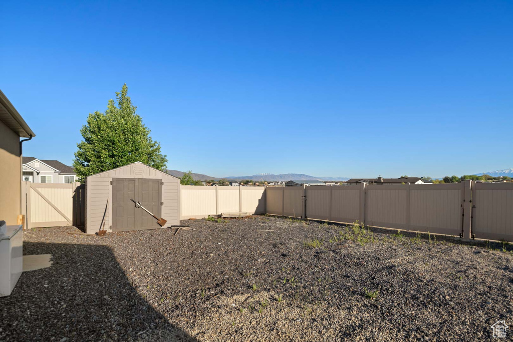 Fenced backyard featuring a storage shed, a gate, an outbuilding, and a mountain view