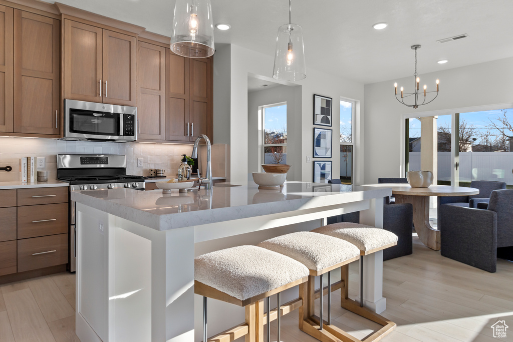 Kitchen featuring stainless steel appliances, recessed lighting, tasteful backsplash, light wood-style floors, and plenty of natural light