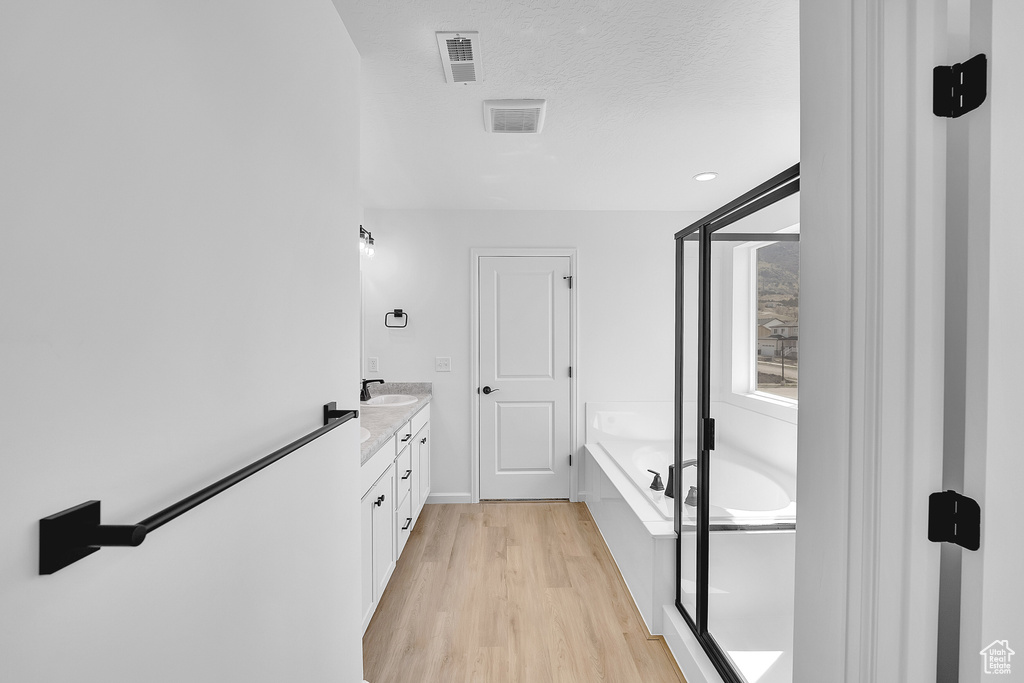 Full bath featuring vanity, wood finished floors, a garden tub, and a shower with door