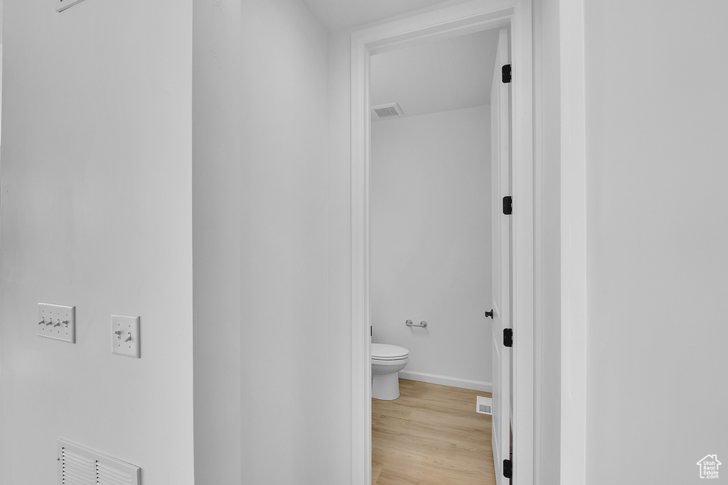 Bathroom featuring toilet, wood finished floors, and baseboards