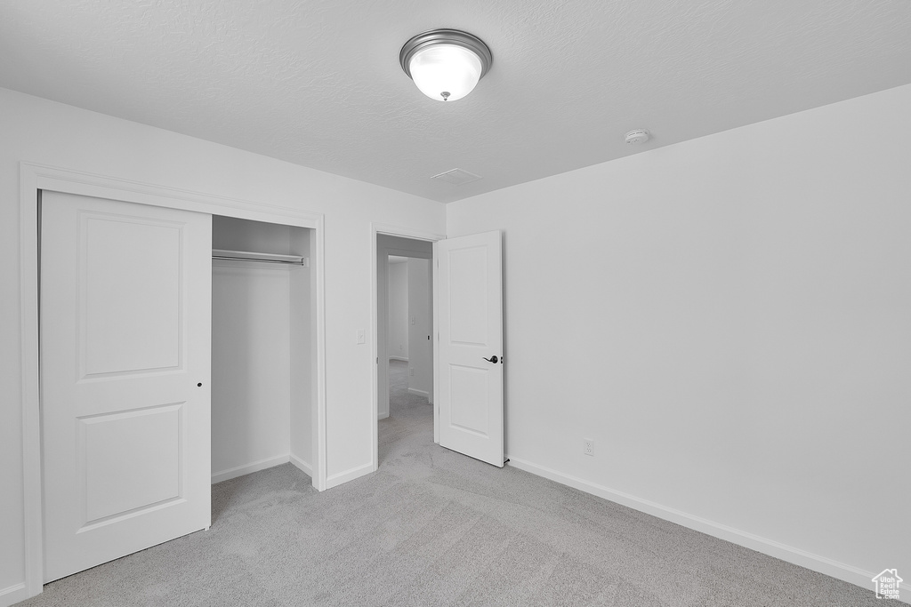 Unfurnished bedroom featuring carpet flooring, baseboards, and a closet