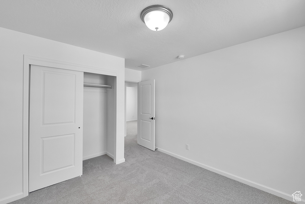 Unfurnished bedroom with carpet floors, a closet, baseboards, and a textured ceiling