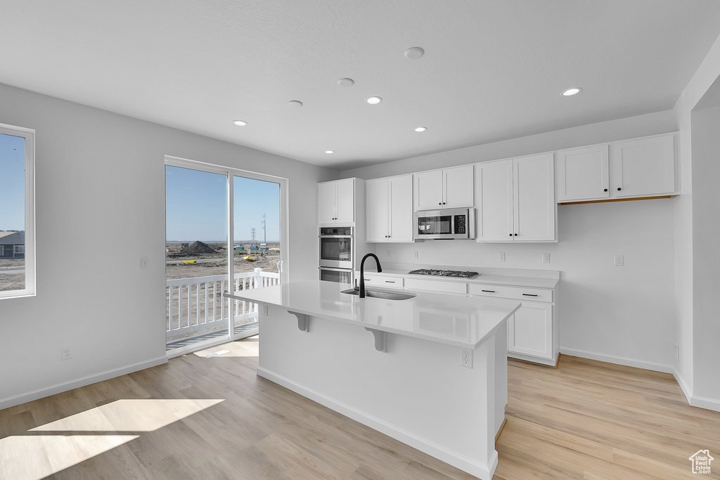 Kitchen with appliances with stainless steel finishes, light wood-style floors, recessed lighting, baseboards, and white cabinetry