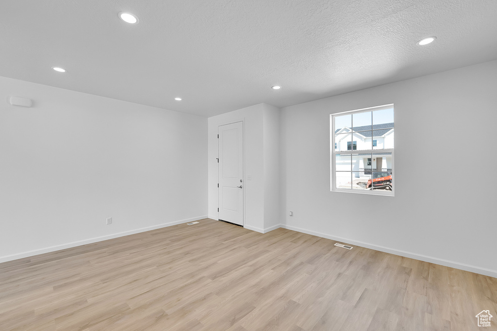 Spare room with light wood-style flooring, recessed lighting, baseboards, and a textured ceiling
