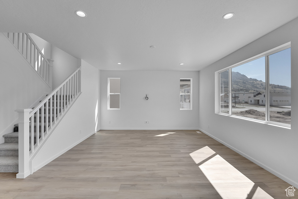 Unfurnished living room featuring stairway, recessed lighting, baseboards, and light wood-style flooring