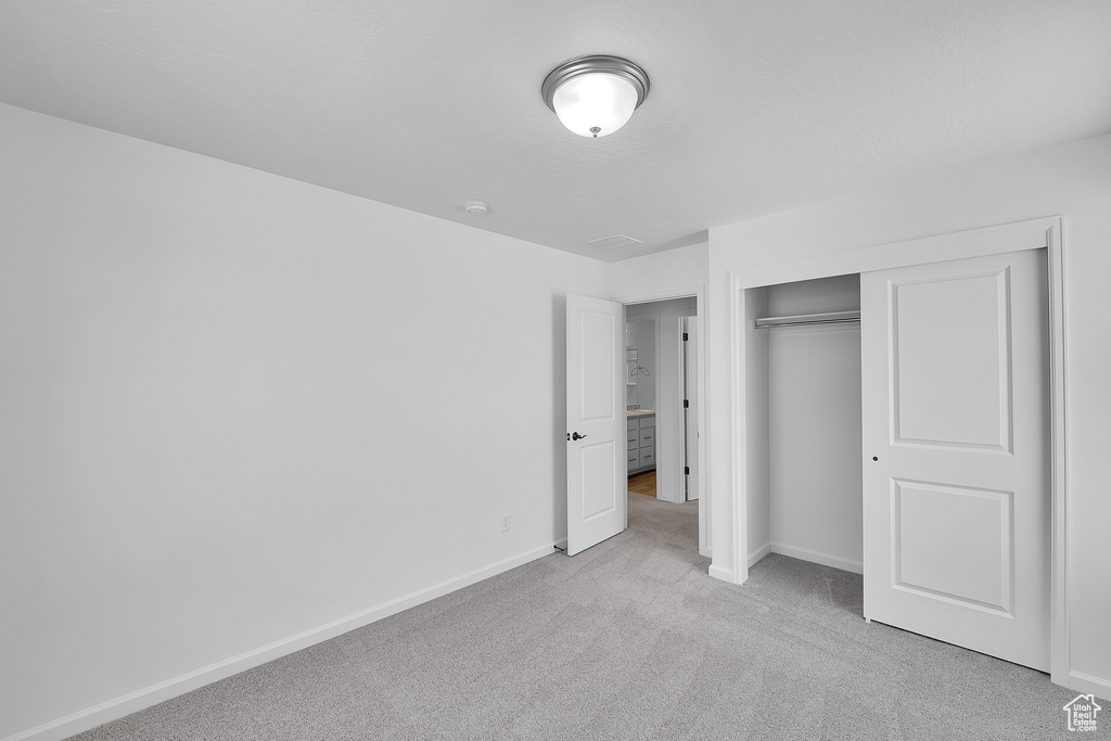 Unfurnished bedroom with carpet floors, baseboards, and a closet