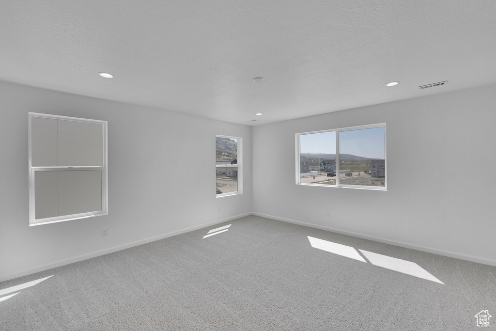 Carpeted spare room with baseboards and recessed lighting