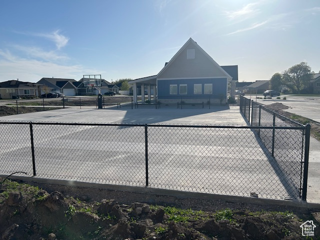 View of tennis court featuring fence and community basketball court