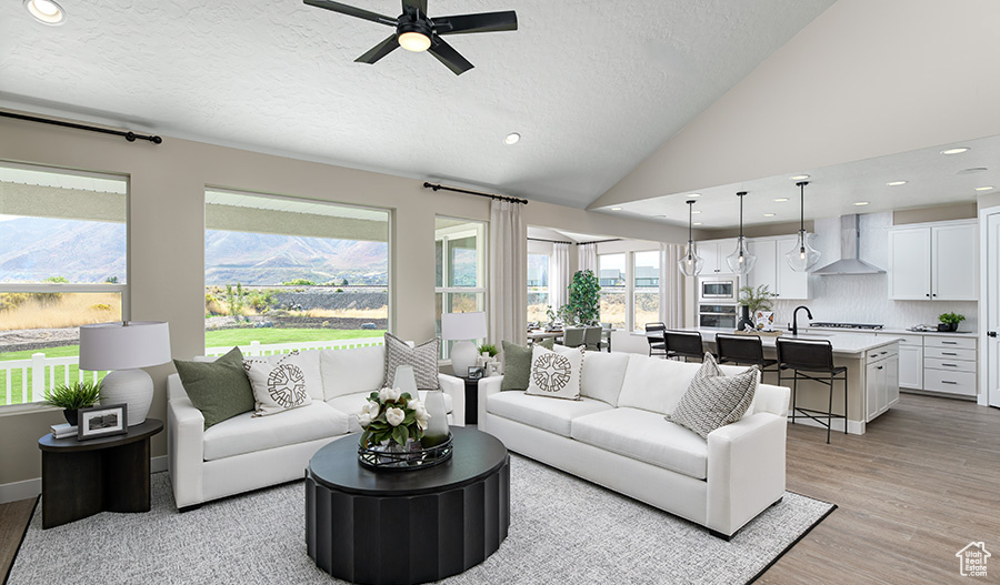 Living area with light wood-style floors, a textured ceiling, a ceiling fan, recessed lighting, and vaulted ceiling