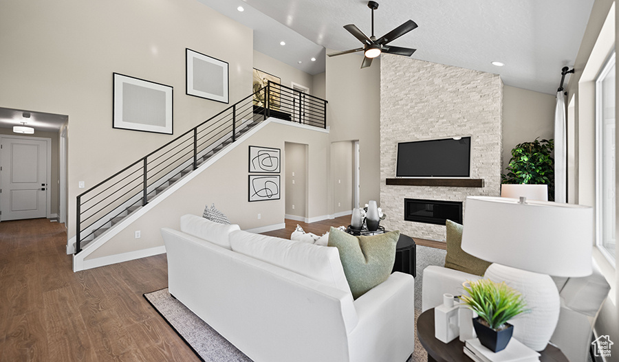 Living area with recessed lighting, wood finished floors, a ceiling fan, stairway, and high vaulted ceiling