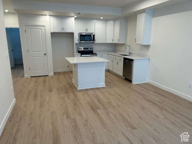 Kitchen featuring stainless steel appliances, a sink, baseboards, light wood-type flooring, and recessed lighting