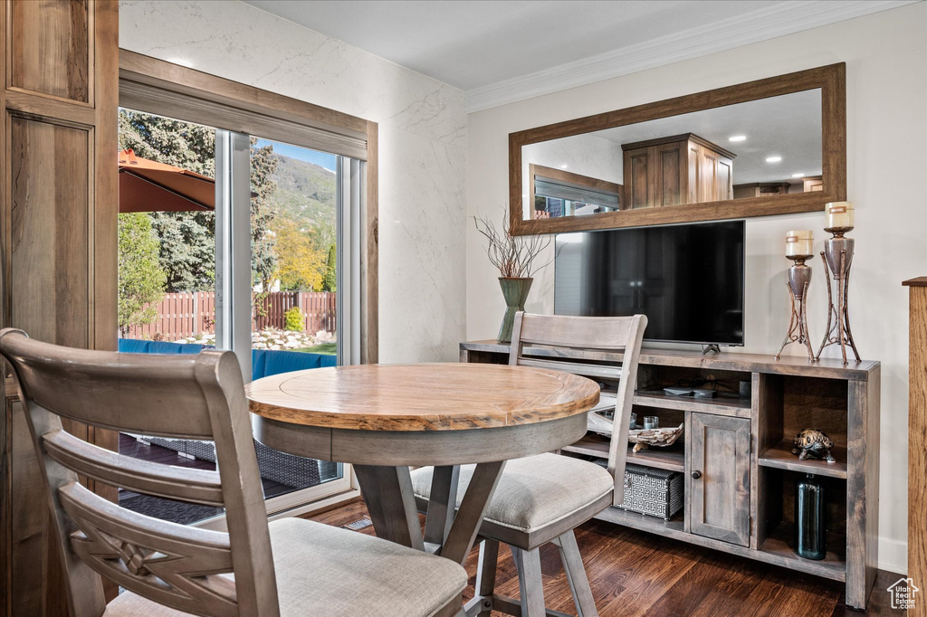 Dining space with dark wood-style floors and crown molding